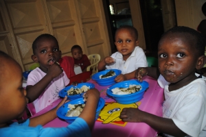 Das schmeckt: Mit den Haenden essen die Kinder ihr Ugali - Maisbrei - und Spinat.